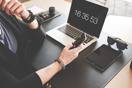 Frau sitzt am Tisch mit Smartphone, Ipad und Laptop